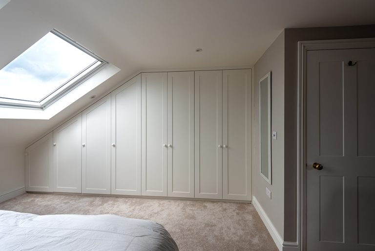 Custom made slanted wardrobe in loft room with 7 doors.