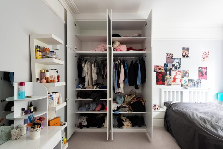 Doors open of a built-in modern white wardrobe