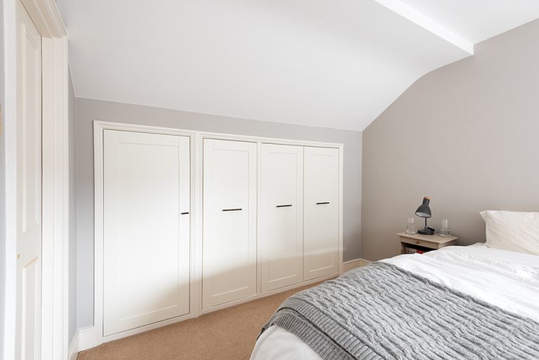 Bespoke white under eaves wardrobe in bedroom.