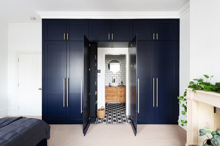 Large built in blue wardrobe with door to bathroom