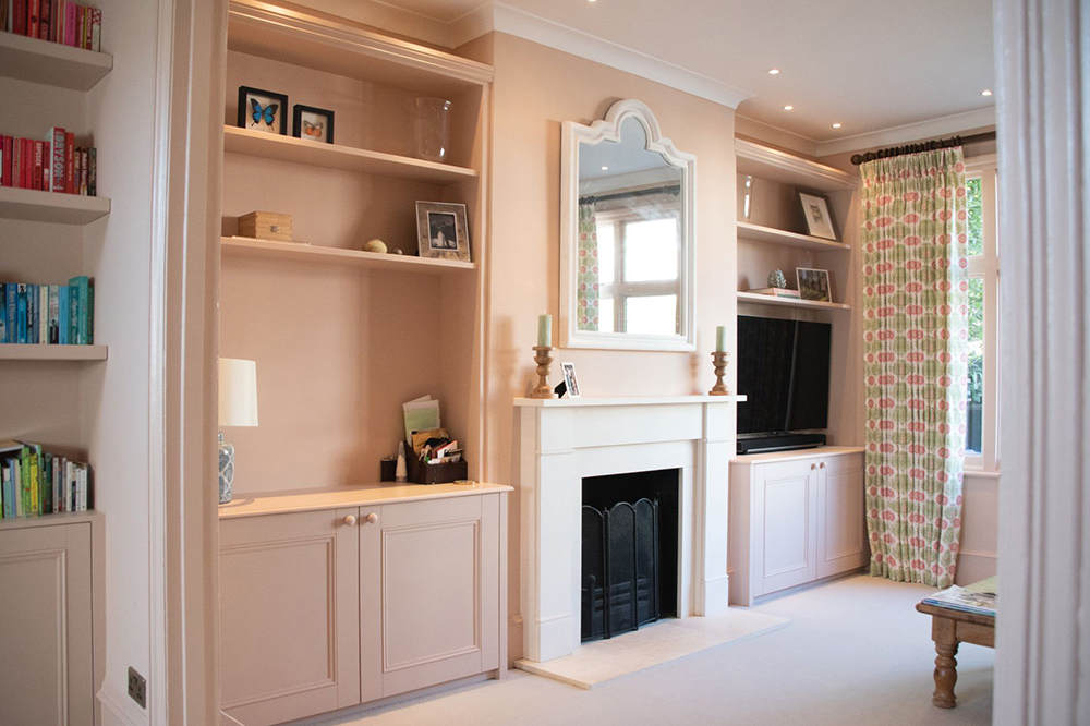 Pink alcove cupboards with floating shelves either side of fireplace