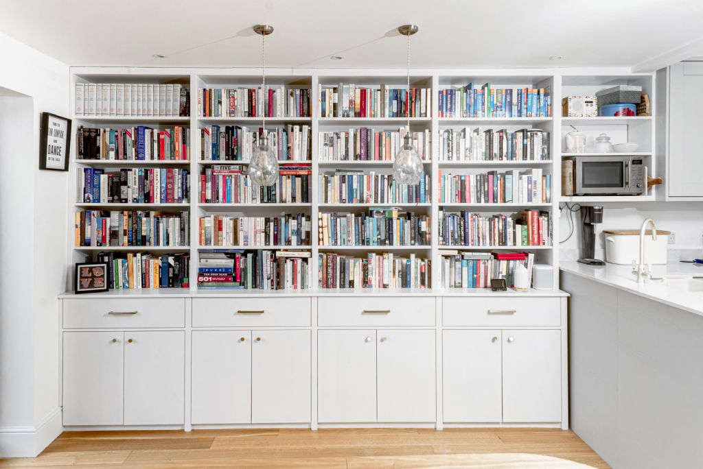 Built-in white bookcase and cupboard near the kitchen. Designed and installed by local carpenters and joiners at Bespoke Carpentry London.