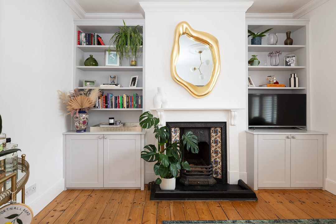 Grey built in alcove cupboard with 7 floating shelves next to fire place to place TV unit and books