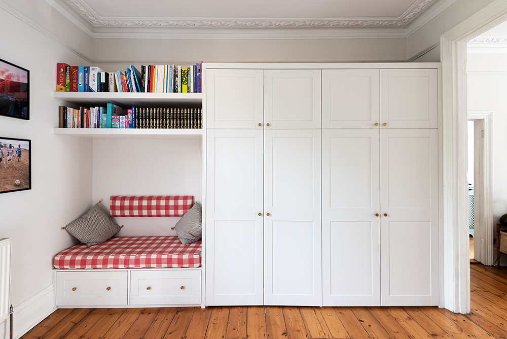 Built in wardrobe with bookshelf and seating.