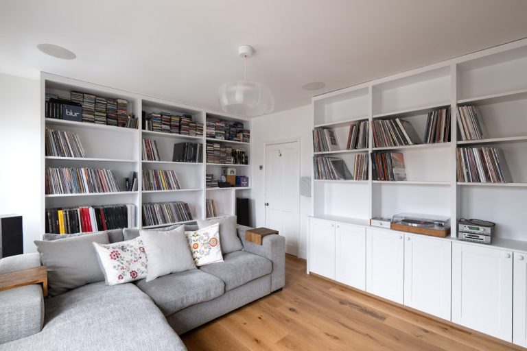 White wall to wall built in cupboards to store music.