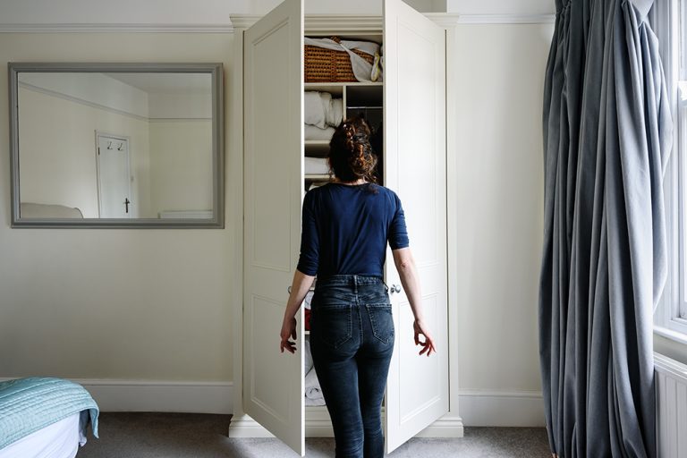 Bespoke wardrobe in alcove space in bedroom and person opening the door