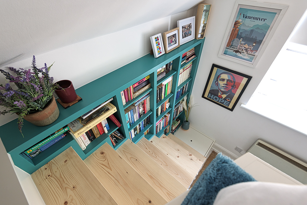 Green built in bookshelf on staircase.