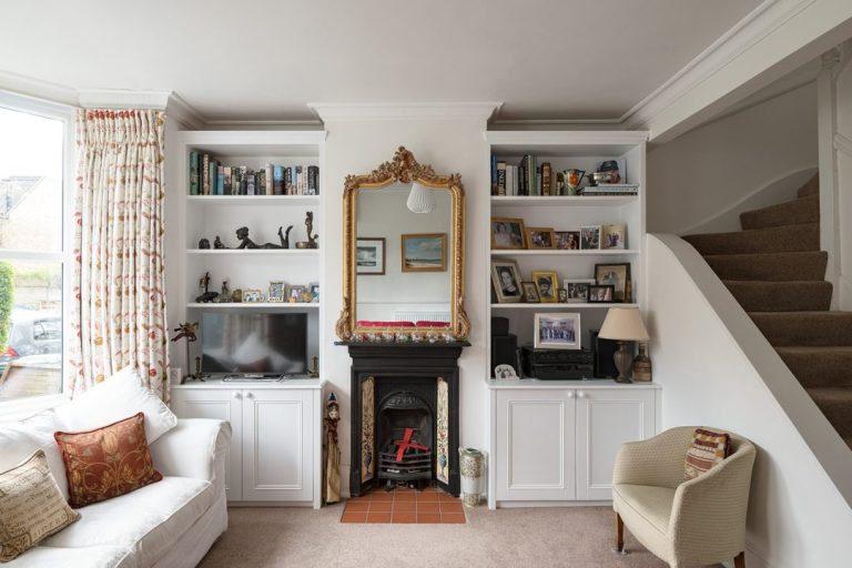 Fitted alcove cupboards with floating shelves on either side of chimney