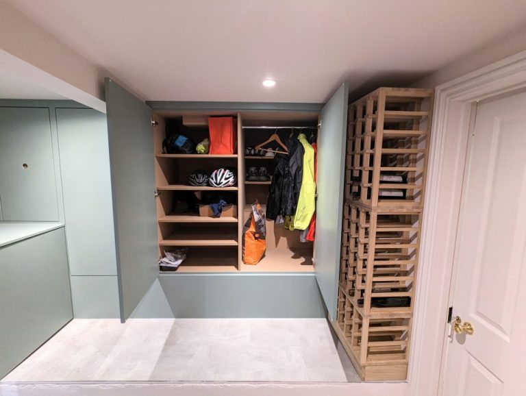 Door open to built in storage cupboards in basement