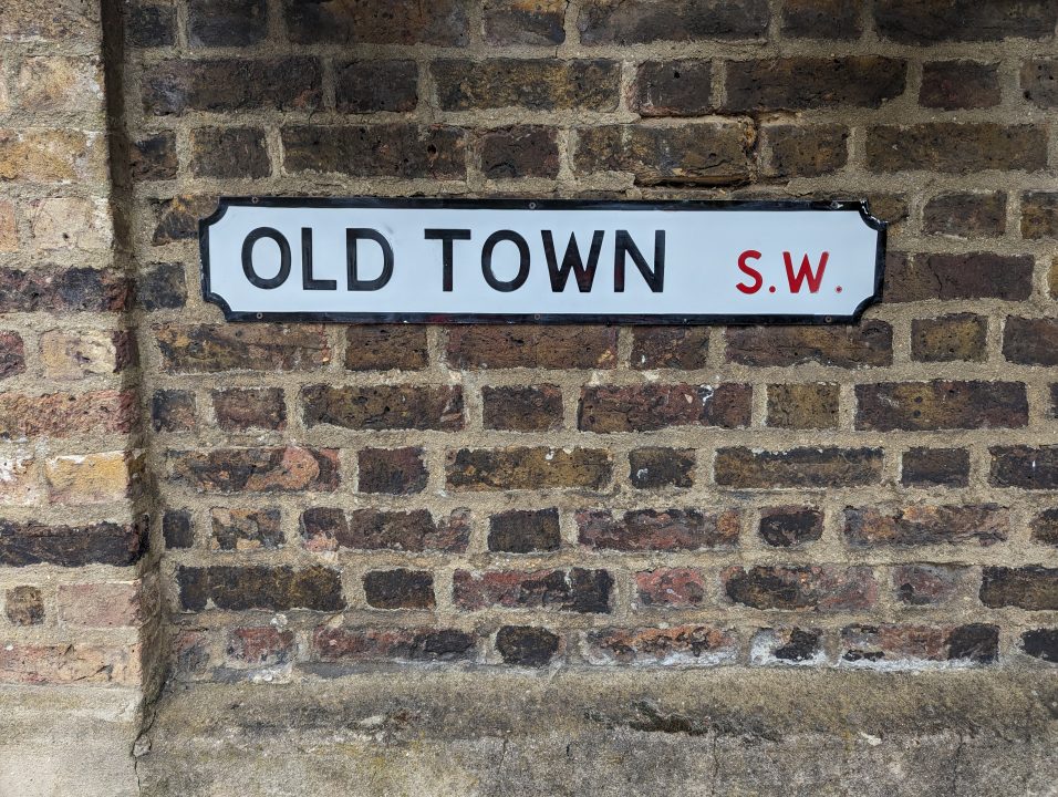 A brick wall with a road sign called Old Town in SW of London