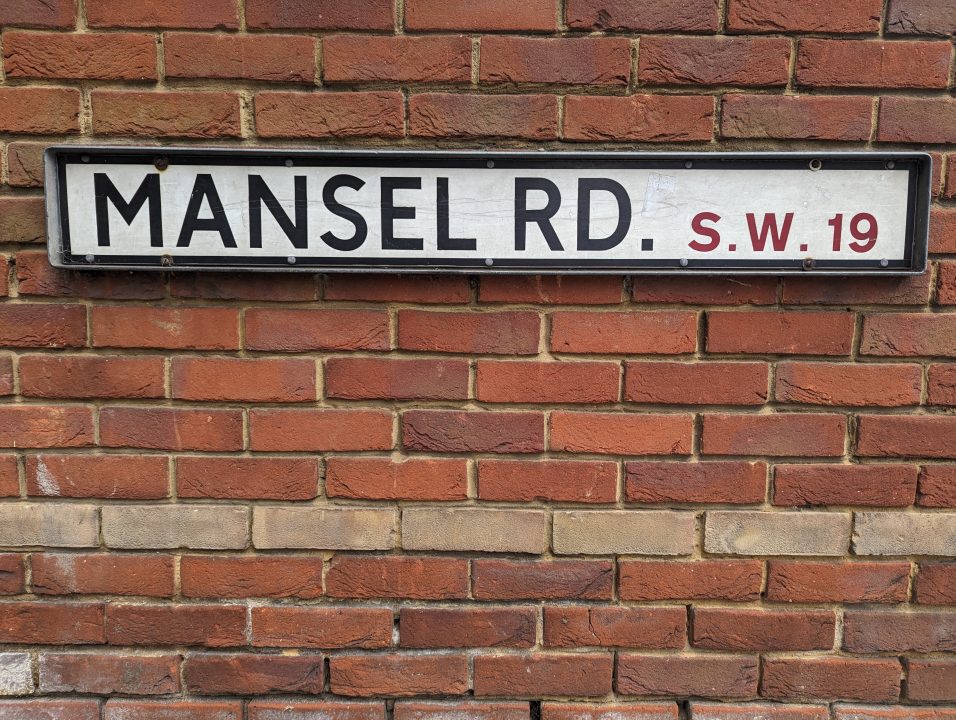 A street sign against a brick wall in Wimbledon