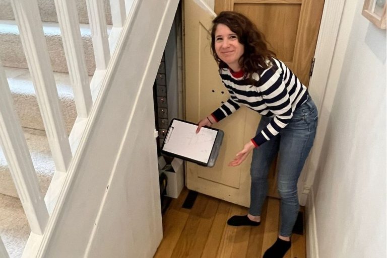 Lady taking measurements of furniture near stairs