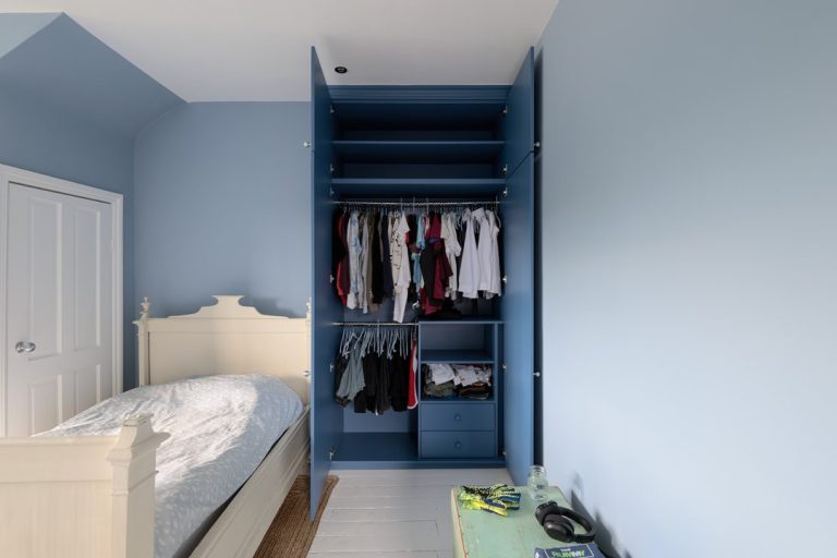 Inside a blue wardrobe with drawers and hanging rail