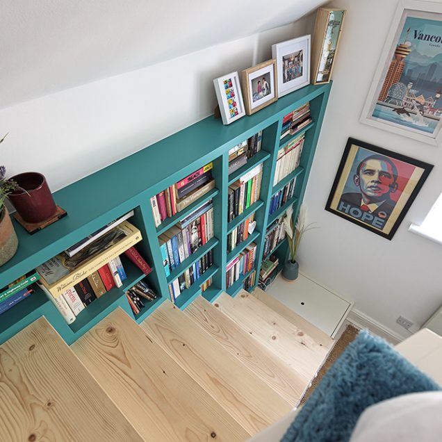 Green built in bookshelf on staircase.