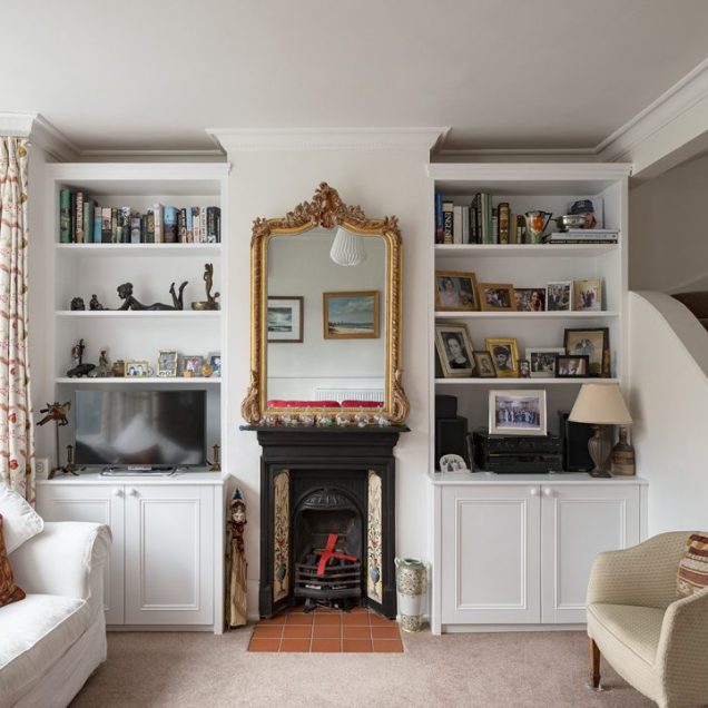 Fitted alcove cupboards with floating shelves on either side of chimney