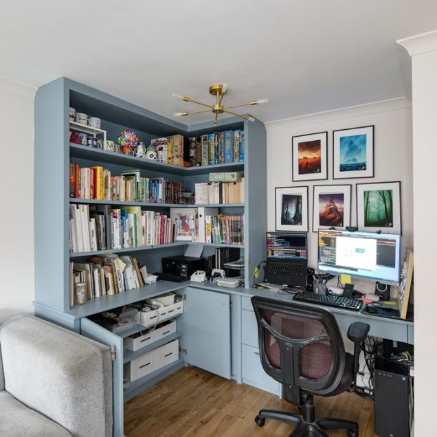 Blue built in home office with desk, cupboards and shelving unit.